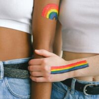 Two arms with LGBT rainbows painted on them.
